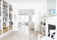 a living room filled with lots of white furniture and bookshelves full of books