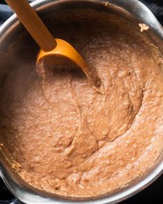 a wooden spoon in a metal pot filled with brown batter on top of a stove