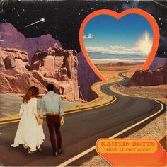 a man and woman are walking down the road in front of a heart shaped sign