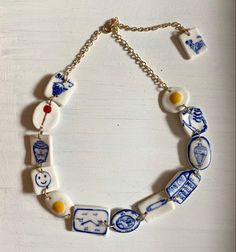 a necklace with blue and white porcelain items on it's link, hanging from a chain