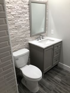 a white toilet sitting next to a sink in a bathroom under a mirror on top of a wooden cabinet