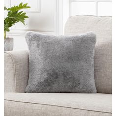 a gray pillow sitting on top of a couch next to a potted green plant