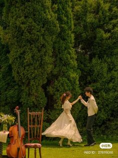 a man and woman are dancing in the grass with their hands together while holding each other's strings