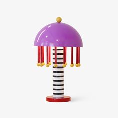 a purple lamp sitting on top of a wooden table next to a black and white striped pole