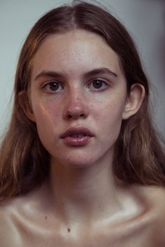 a young woman with freckled hair and no shirt is looking at the camera