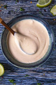 a bowl filled with white sauce next to sliced limes