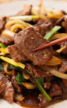 beef and vegetable stir fry with chopsticks on a plate