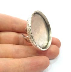 a hand holding a silver ring with filigrees on the outside and inside