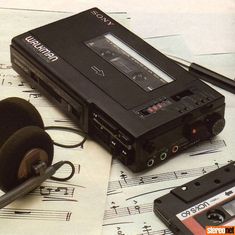 an old tape recorder sitting on top of music sheets with headphones next to it