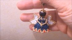 someone is holding a beaded keychain with an angel charm attached to it