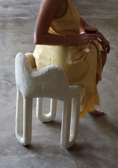 a woman in a yellow dress is sitting on a white chair with a wine glass