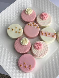 some pink and white decorated cupcakes on a plate with gold bead trim