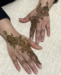 two hands with henna tattoos on them