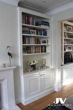 a living room with bookshelves and fireplace in the corner, white painted walls