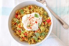 a white bowl filled with rice and veggies next to a spoon on top of a table