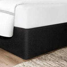 a bed with white sheets and black trim on the bottom half is shown in this image