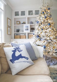 a living room with a christmas tree in the corner and pillows on the couches