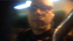 a blurry photo of a man with glasses and a cell phone in his hand