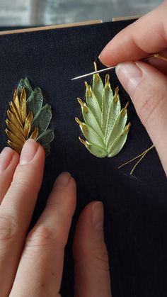 someone is working on something with gold and green leafy decorations in their hands,