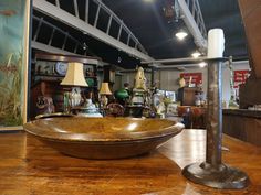 a large metal bowl sitting on top of a wooden table next to lamps and pictures