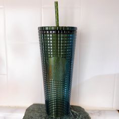 a green starbucks cup sitting on top of a marble counter next to a white tile wall