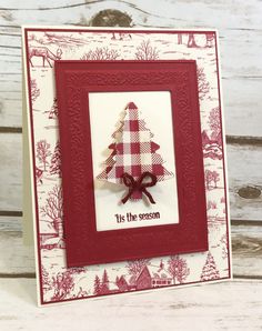 a red and white card with a christmas tree in the center, it's the season