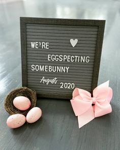 an egg nest with two eggs in it next to a sign that says we're expecting somebunny august