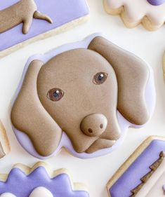 cookies decorated like dogs and bones on top of a white tablecloth with purple icing