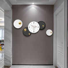 a wall with three clocks on it in front of a gray wall and white door