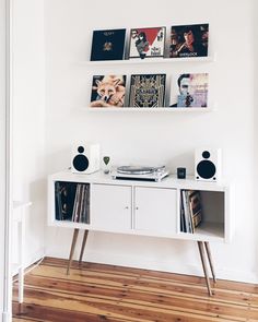 a white entertainment center with records on the wall