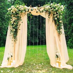 an outdoor wedding ceremony setup with white drapes and flowers on the back drop cloth