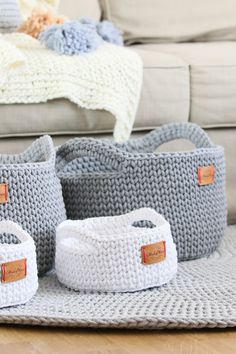 three crocheted storage baskets sitting on top of a rug next to a couch