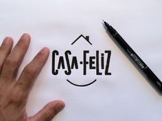 a person's hand next to a pen and paper with the word caa - feliz written on it