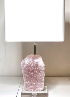 a pink lamp sitting on top of a table next to a white square light shade