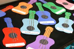 colorful guitars are arranged on a black table with name tags in the shape of them