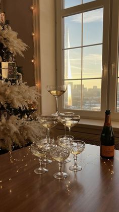 three glasses of wine on a table in front of a christmas tree and a window