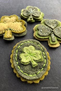 four green and yellow felt shamrocks sitting on top of a black table next to each other