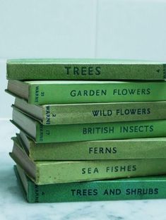 a stack of green books sitting on top of a white marble counter next to each other