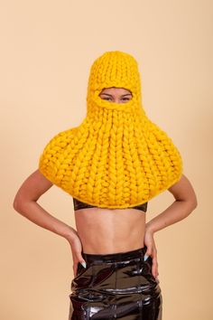 a woman wearing a yellow knitted hood and skirt with her hands on her hips