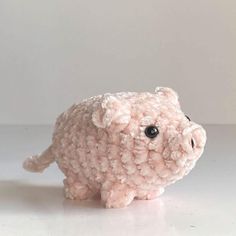 a pink stuffed animal with black eyes on a white surface