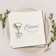 two napkins sitting on top of a white plate next to green leafy stems