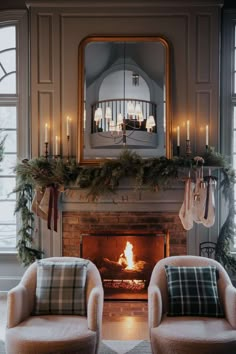 two chairs sitting in front of a fireplace with stockings hanging from it's mantle