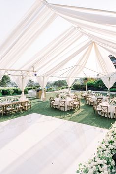 a white tent with tables and chairs set up for an outdoor wedding reception in the sun