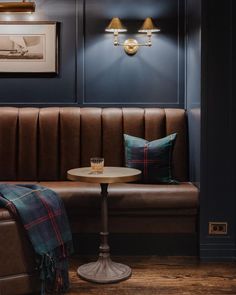 a table with a glass on it sitting next to a brown leather couch in a room