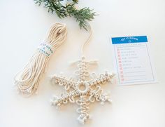 a snowflake ornament next to a christmas tree branch with a tag on it