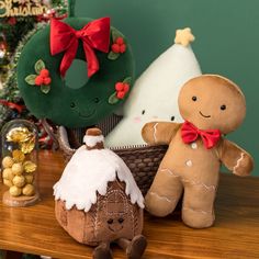 three gingerbread man and woman stuffed animals on a table next to a christmas tree