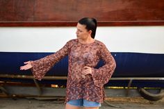 a woman standing in front of a boat with her hands out to the side,