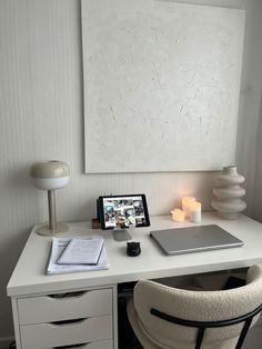 a laptop computer sitting on top of a desk next to a white chair and lamp