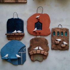 four clay pieces with birds on them hanging from hooks and one has a birdhouse in the middle