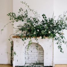 a white brick fireplace with greenery on top